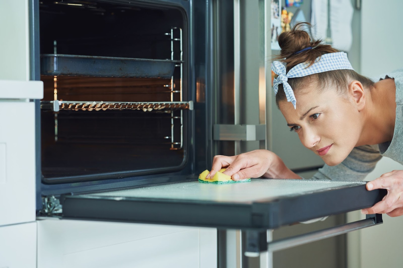 Photo of a woman using a sponge for oven cleaning