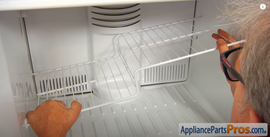 Hands lifting a wire shelf out of a freezer compartment