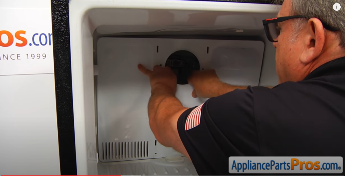 Technician unlatching the plastic fan cover from the freezer's rear wall