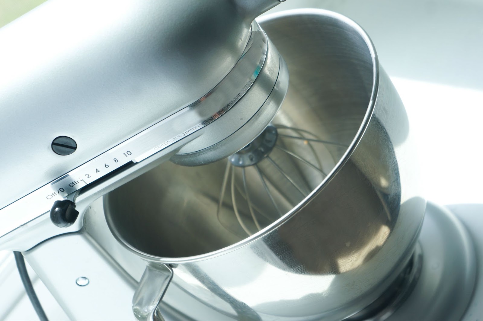 Stand mixer with a stainless bowl, wire whisk attachment, and speed control lever