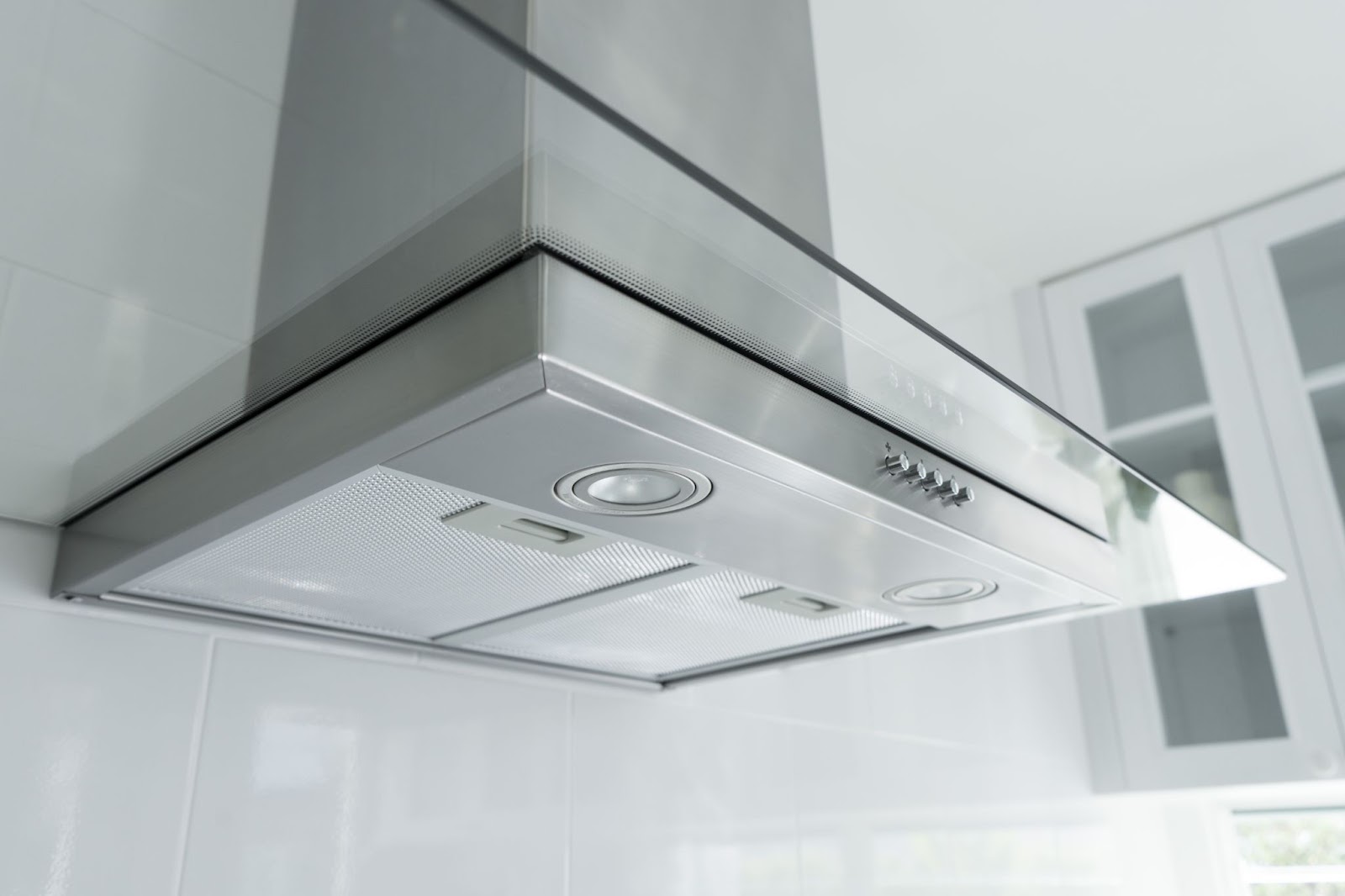 Underside of a stainless range hood showing mesh filters, lights and buttons