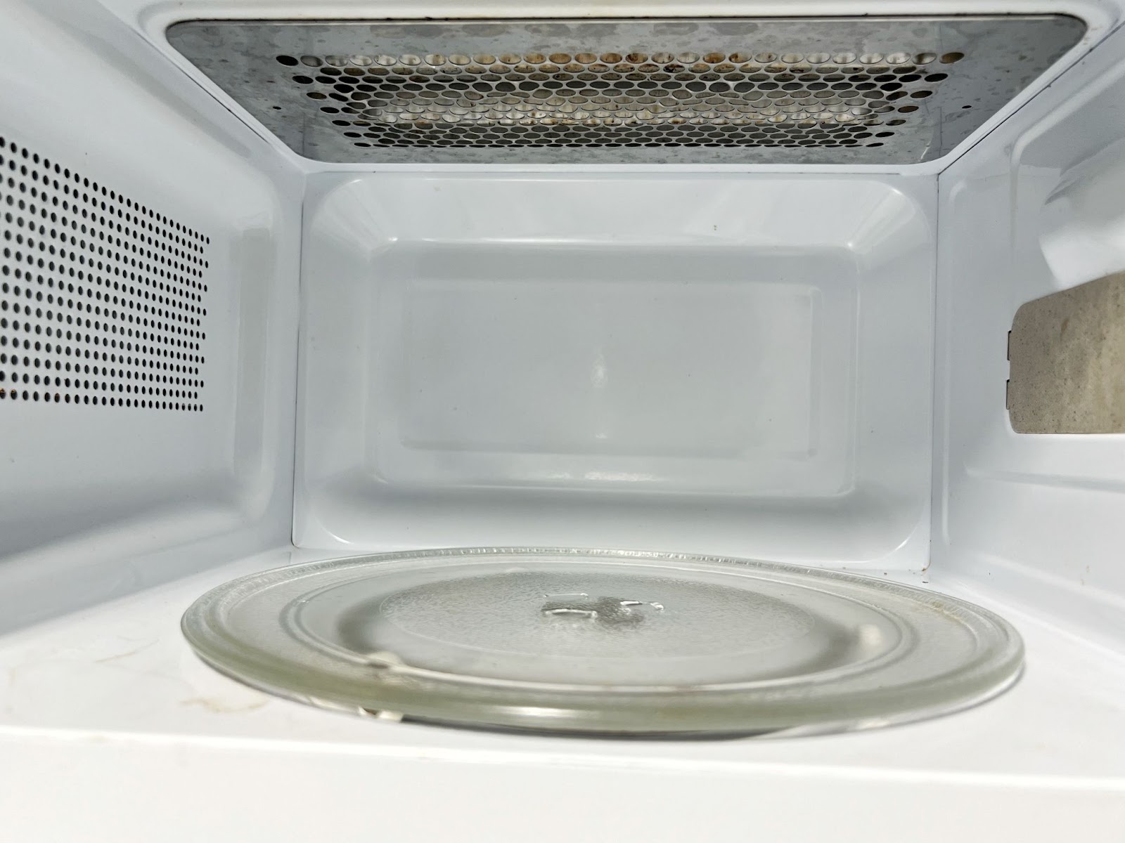 Glass turntable plate inside an empty white microwave cavity