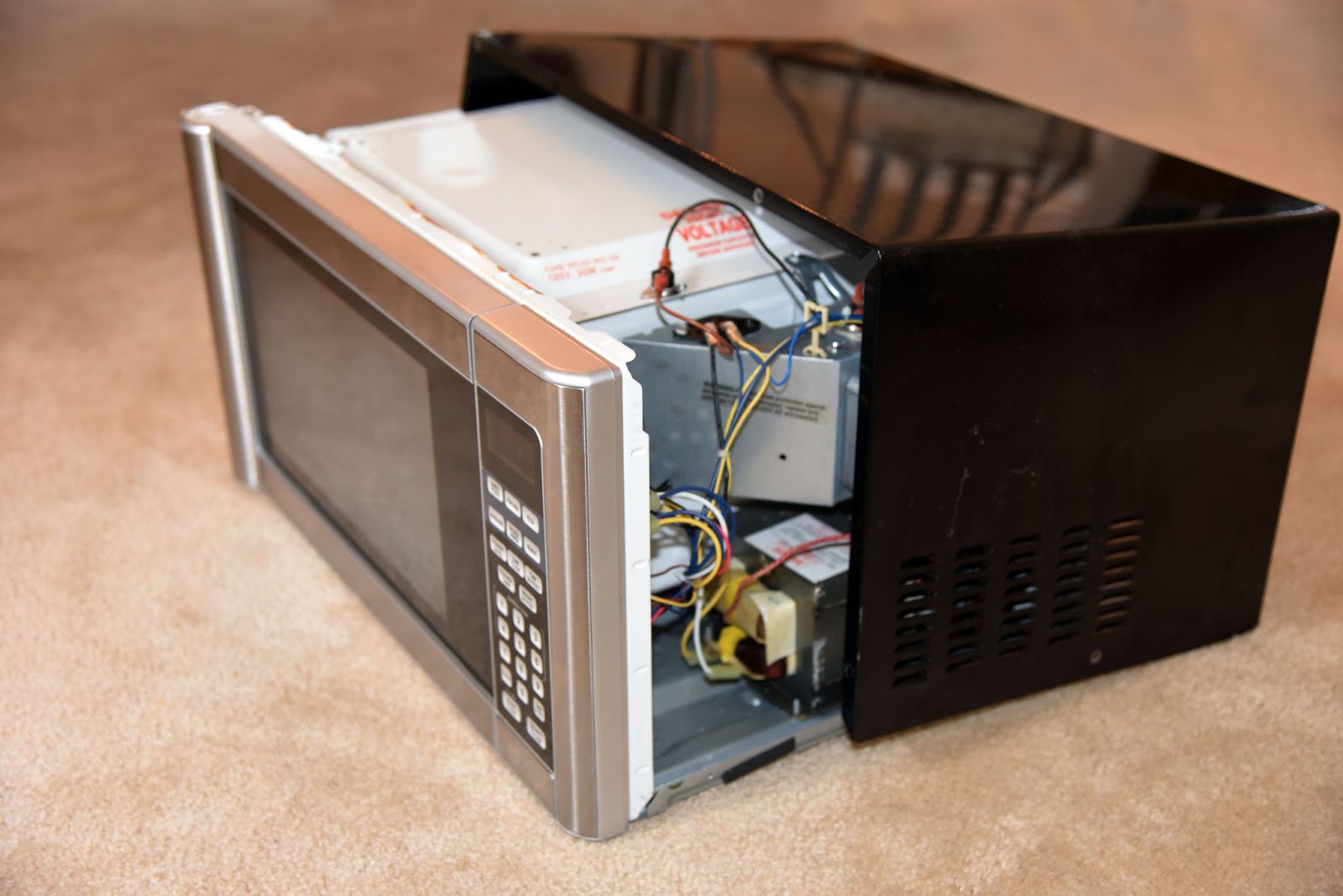 Microwave with its outer cover removed, exposing the transformer, wiring, and internal components