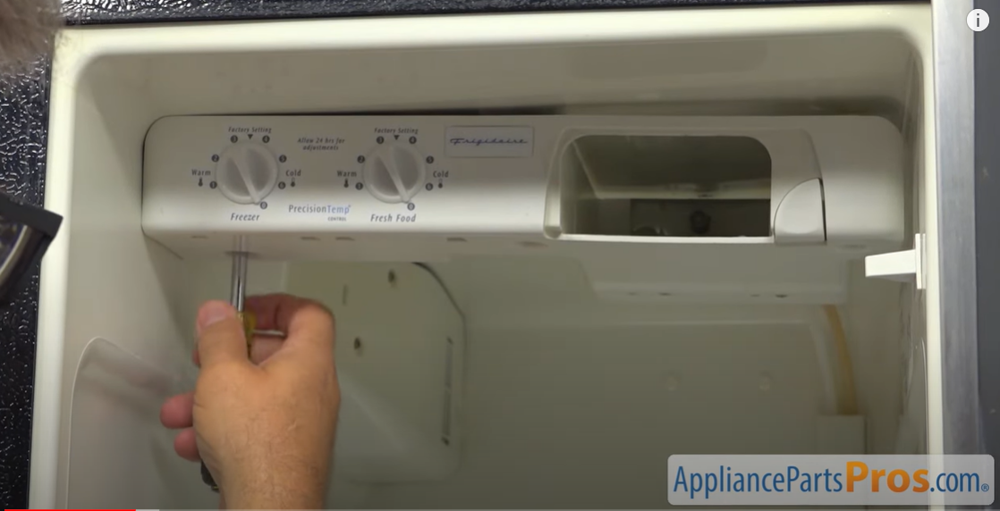 Screwdriver beneath the freezer and fresh food temperature dials on a refrigerator control panel
