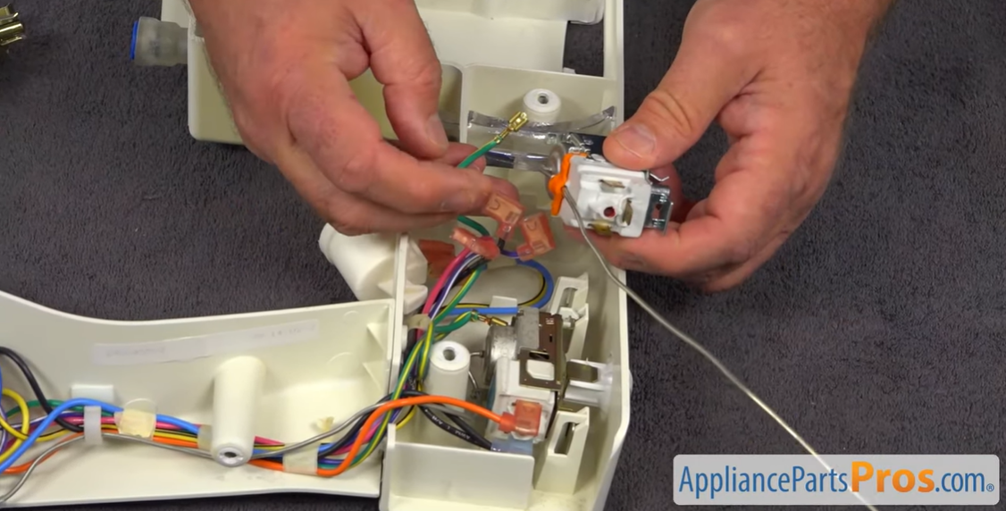 Hands connecting wire terminals to a new refrigerator temperature control thermostat