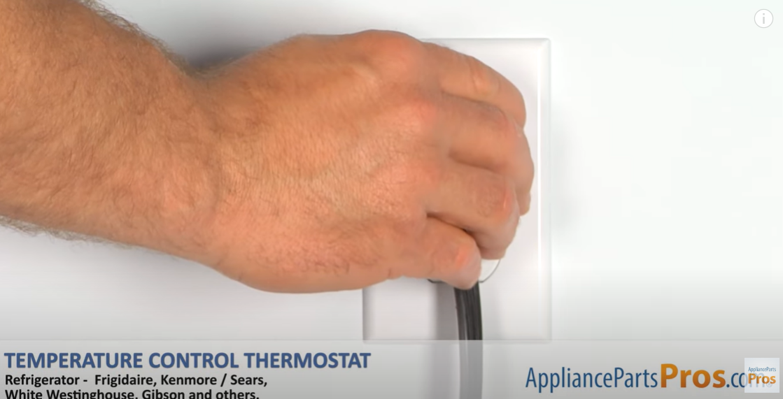 Hand plugging a refrigerator power cord into a white wall outlet