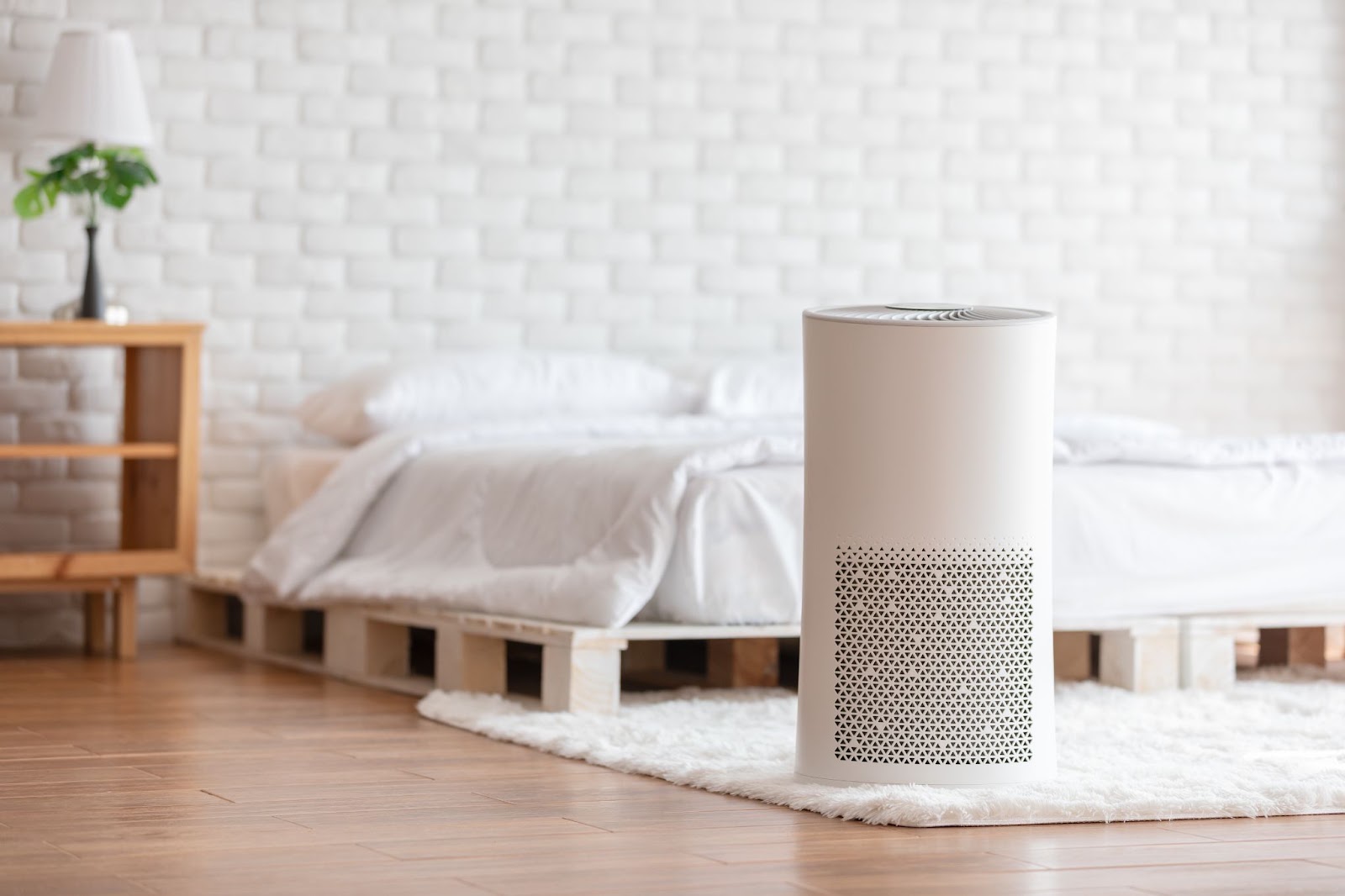 White cylindrical air purifier on a wood floor in a bedroom